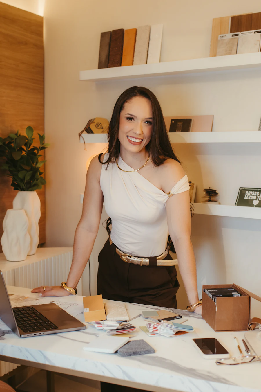 Rhea standing at her studio desk among print samples